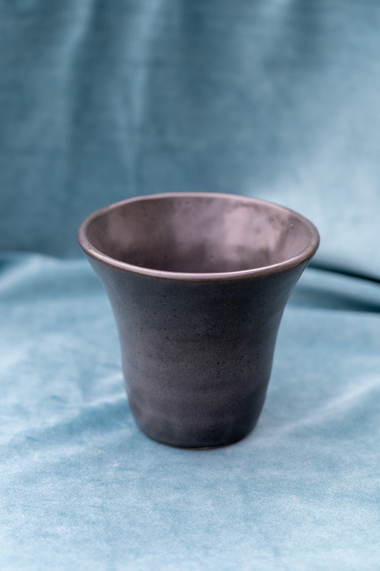 Charcoal ceramic cup on a blue fabric background