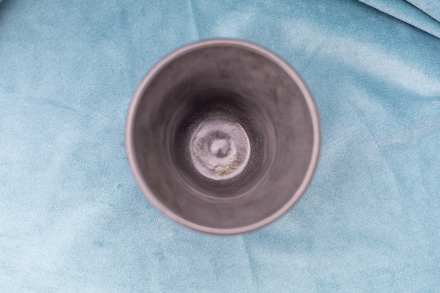 Gray ceramic cup on a textured blue surface