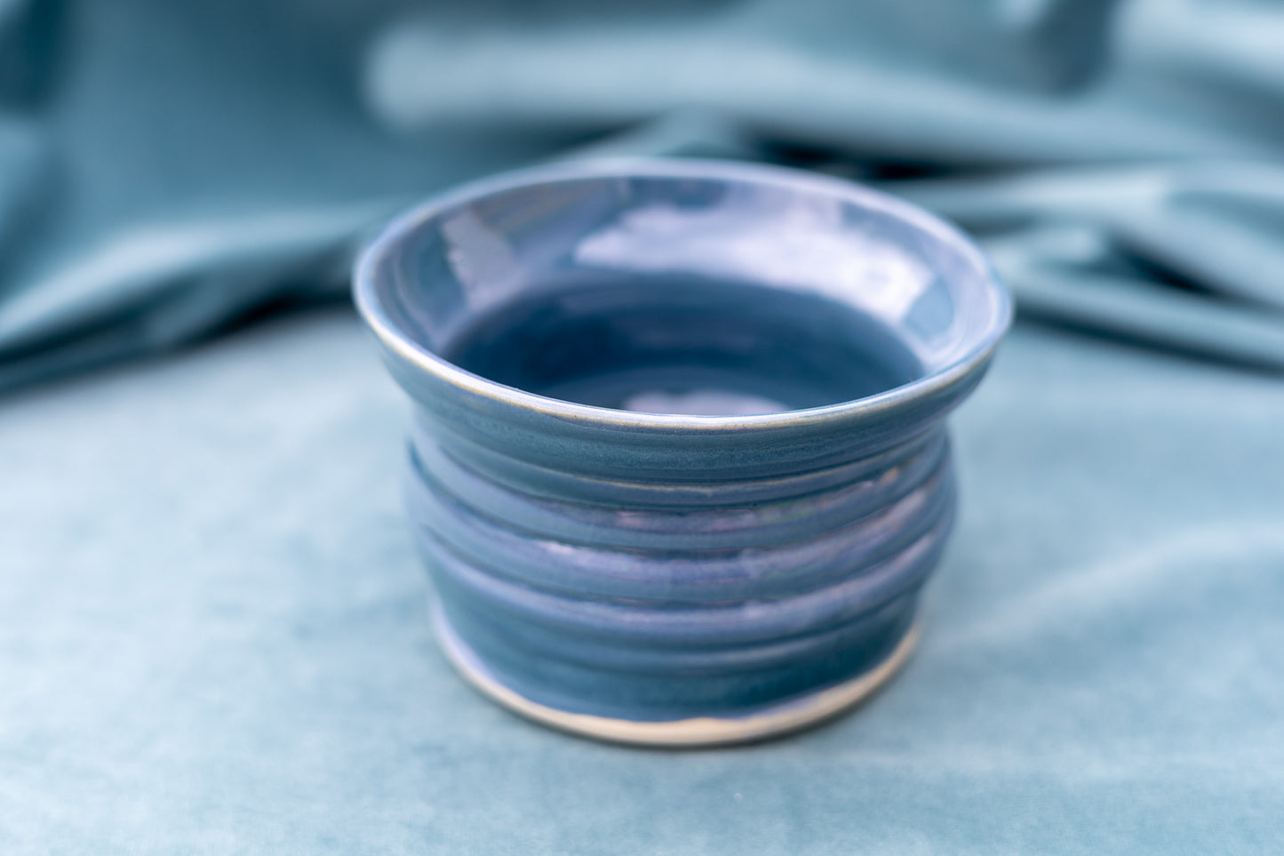 Blue ceramic cup on a blue fabric background